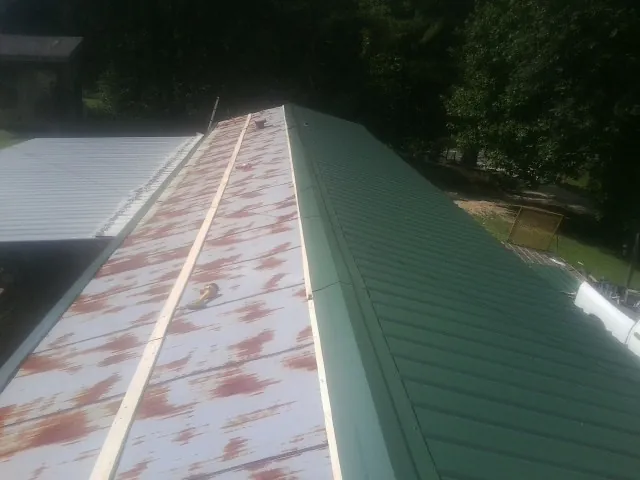 Old rusted panels beside newly installed green metal roofing — Wind Damage Roof Repair by Roofing Brothers in Durant