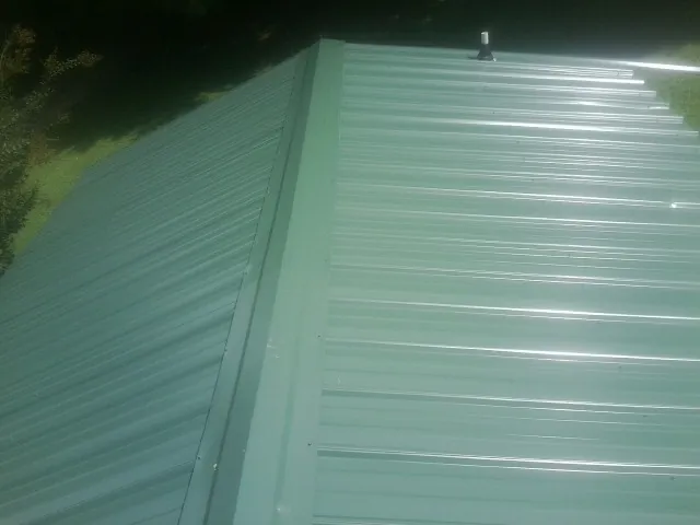 New green metal panels meeting at the ridge of a roof — Flat Roof Repair work by our crew in Durant