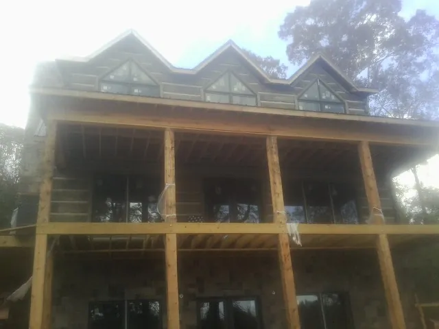 Dormers and porch framing on a large log home under construction — Roof Coating work by our crew in Durant